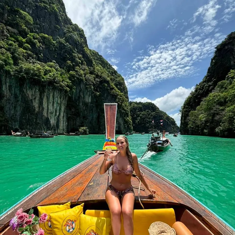 นักท่องเที่ยวนั่งบนหัวเรือหางยาวที่แต่งพร็อพ ระหว่างผาหินปูน